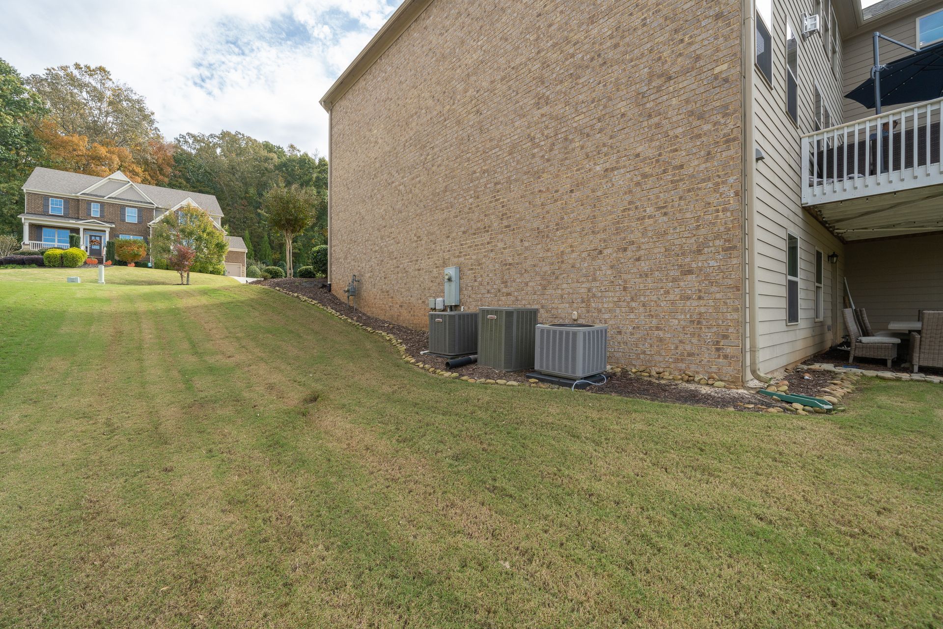 A large brick house with a large lawn in front of it.