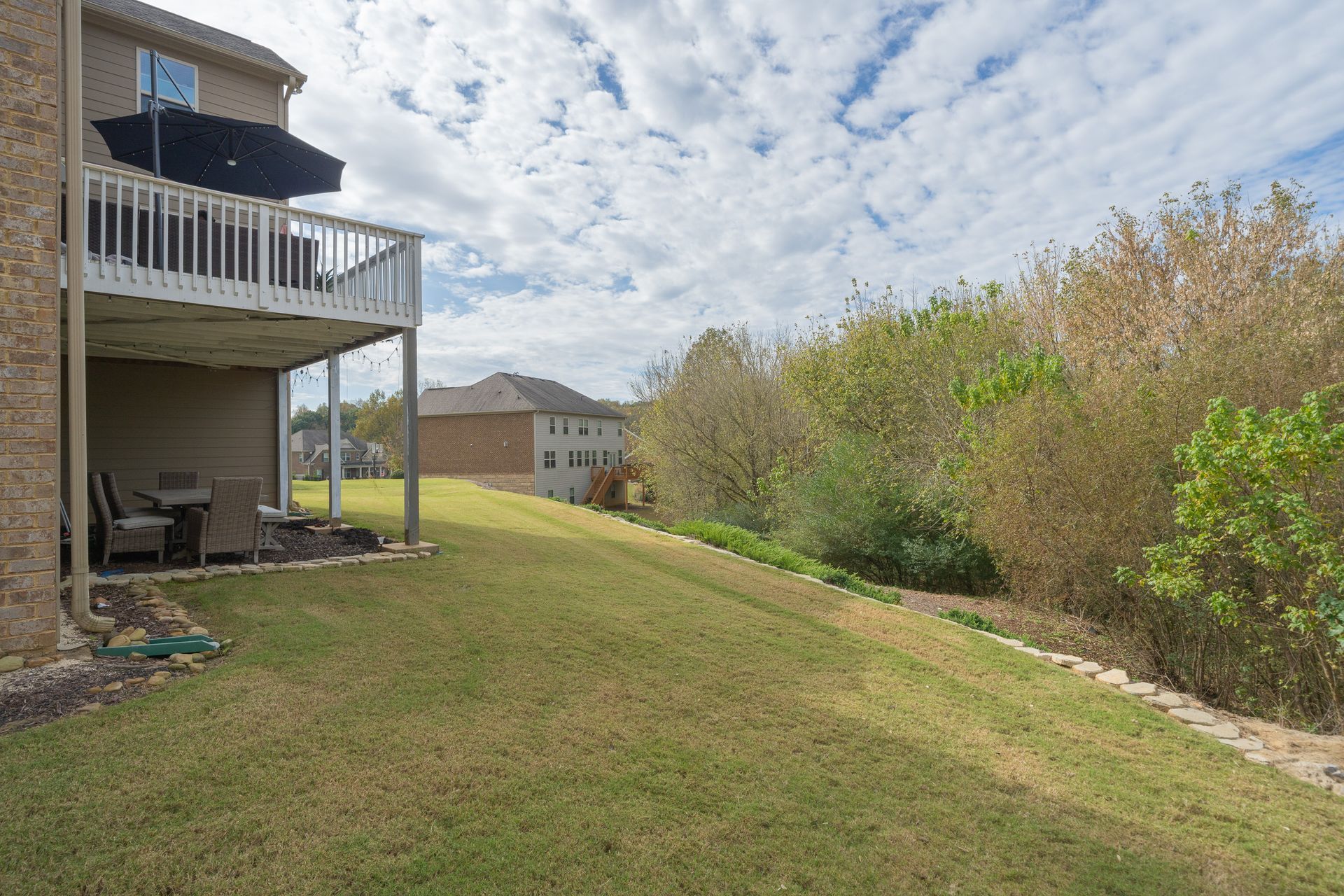 The backyard of a house with a large lawn and a deck.