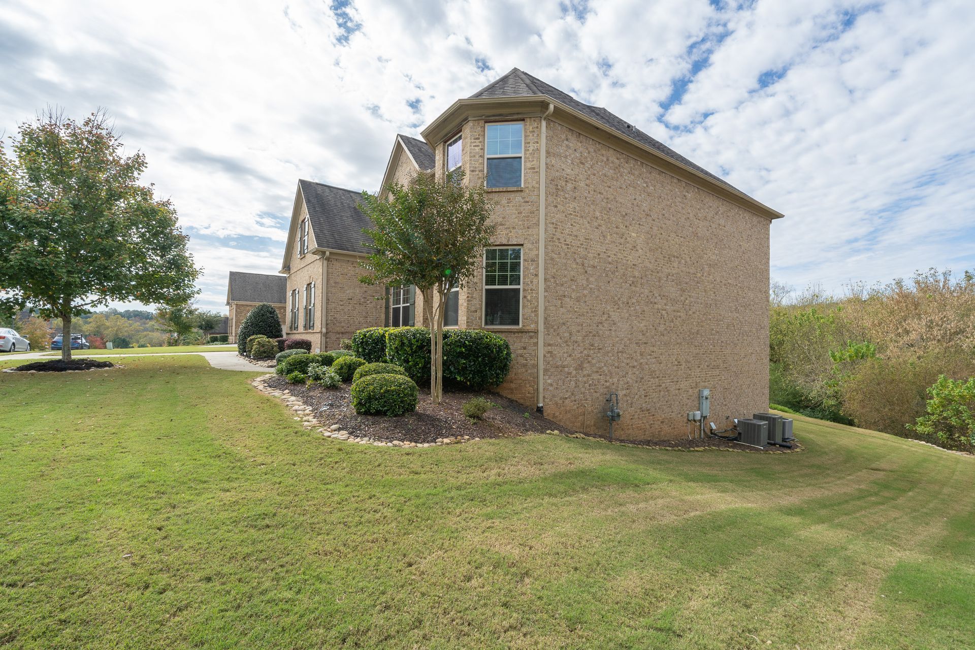 A large brick house with a large lawn in front of it.