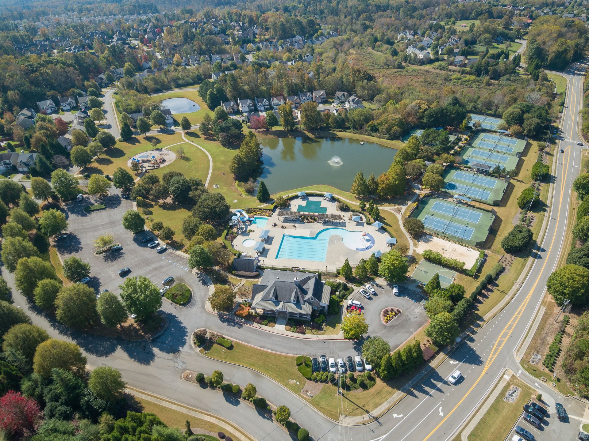 An aerial view of a residential area with a swimming pool and tennis courts.