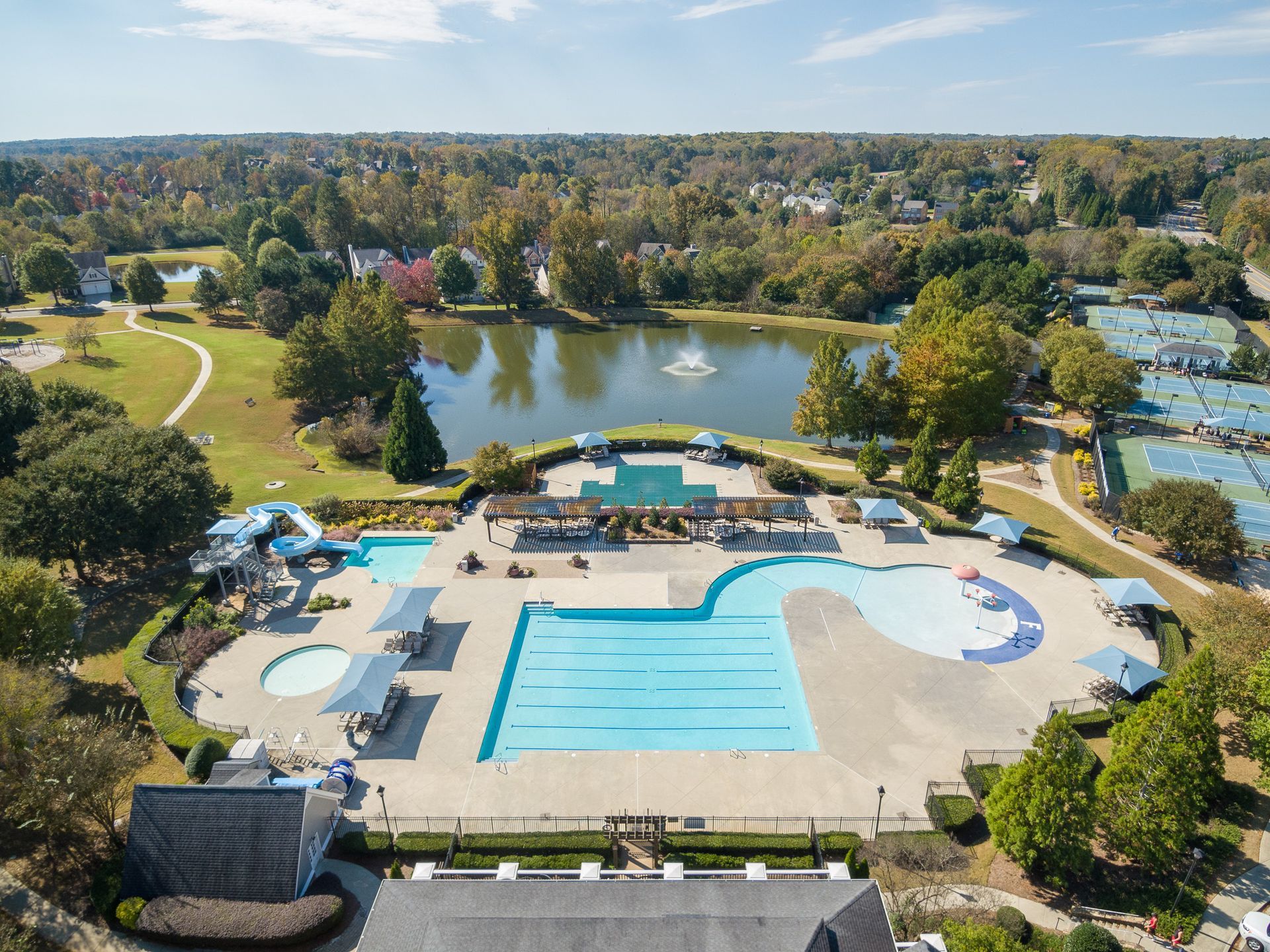 An aerial view of a large swimming pool surrounded by trees and a lake.