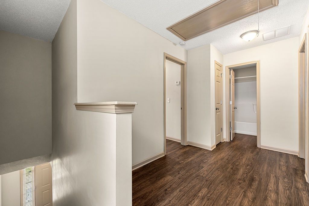 A hallway with hardwood floors and white walls in a house.