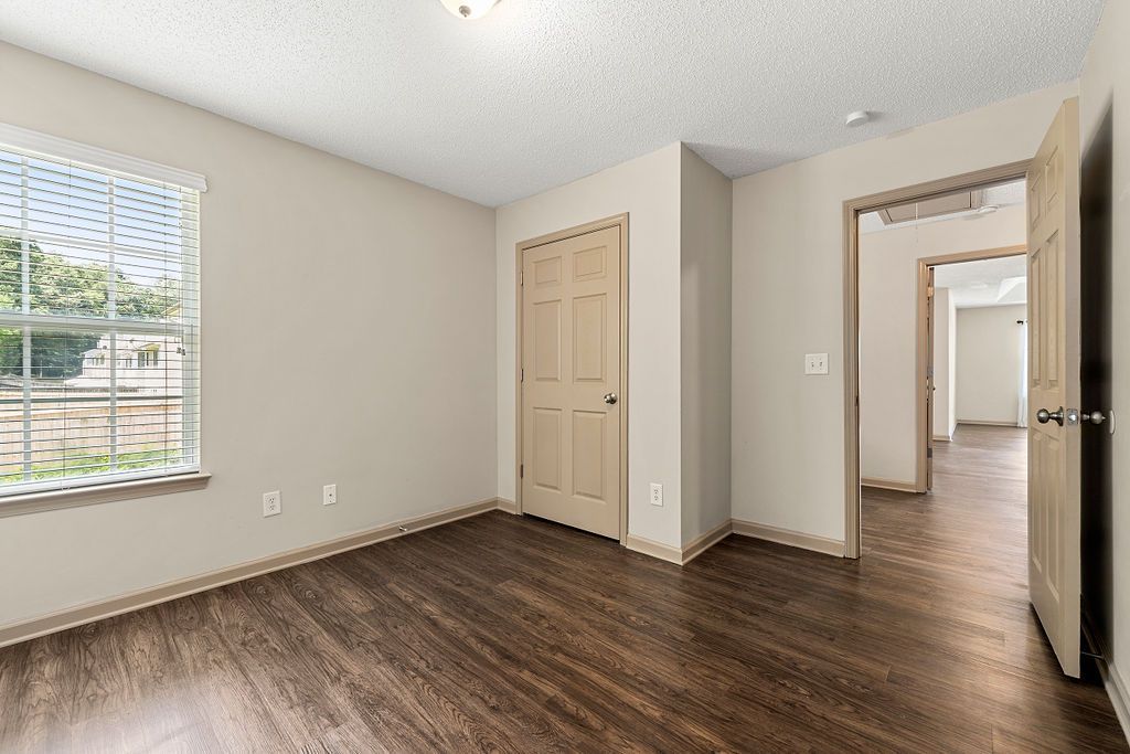An empty living room with hardwood floors and a window.