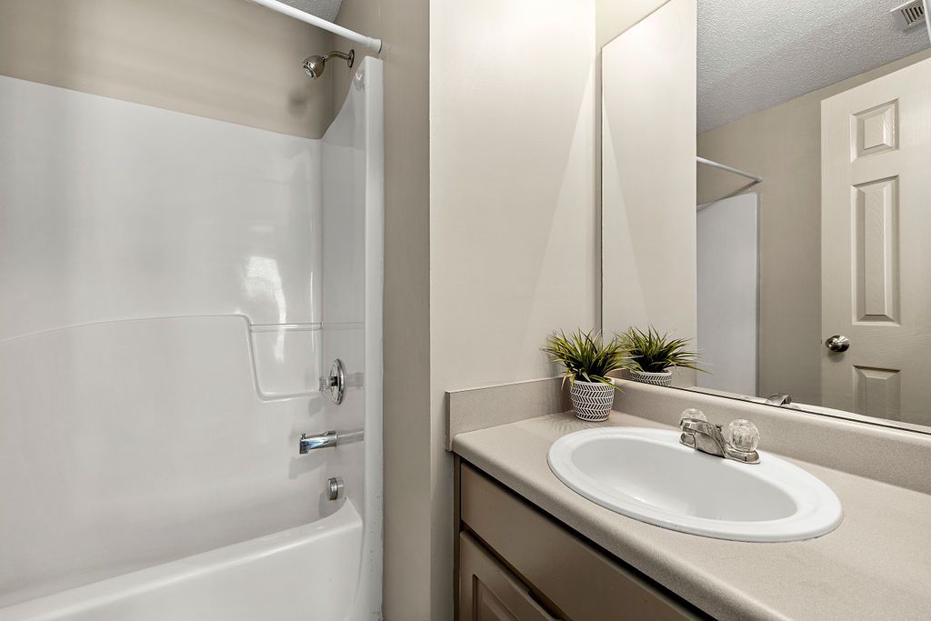 A bathroom with a sink , tub and mirror.
