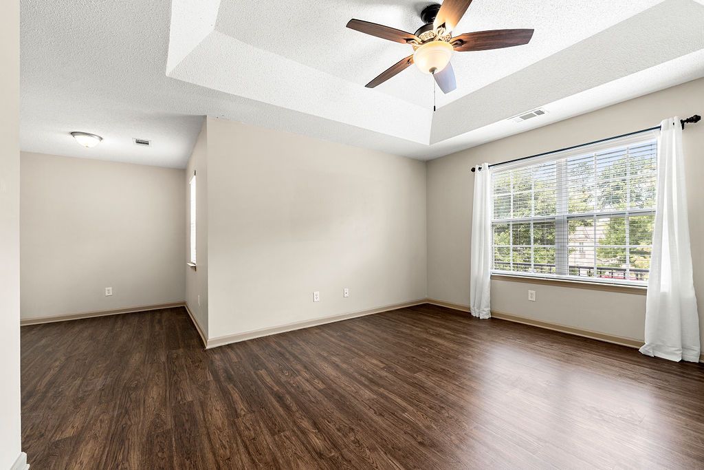 An empty living room with hardwood floors and a ceiling fan.