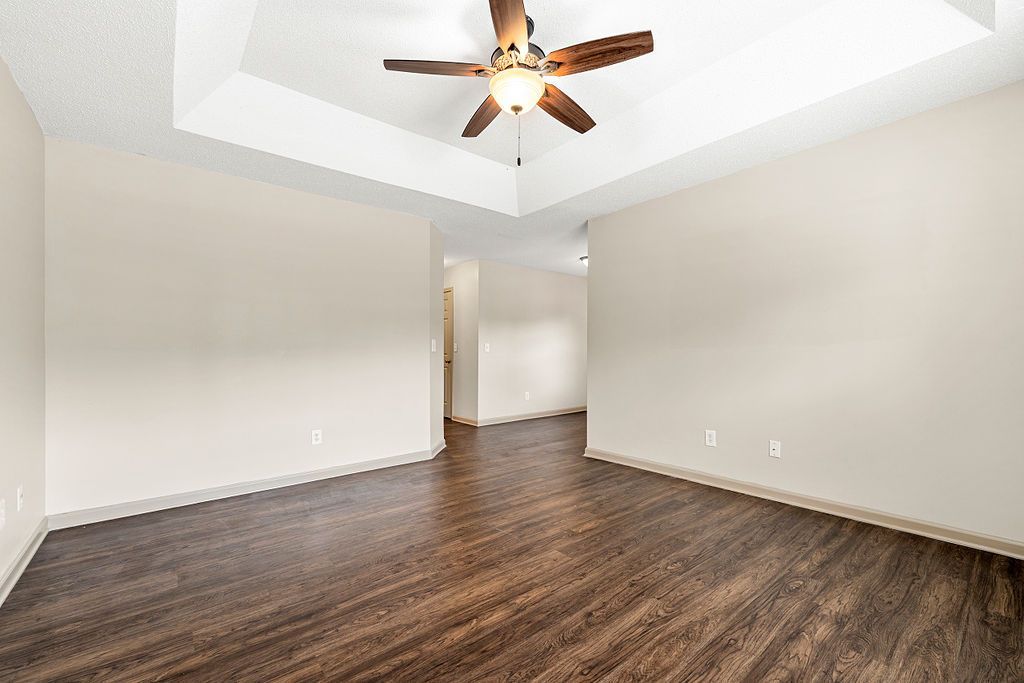 An empty living room with hardwood floors and a ceiling fan.
