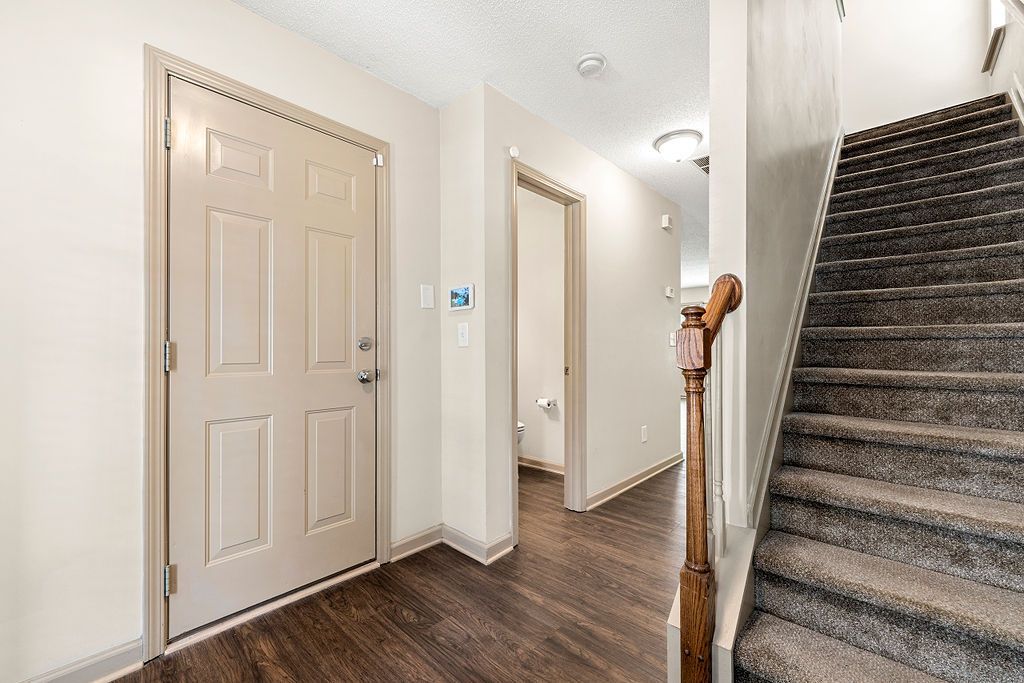 A hallway with a door and stairs in a house.