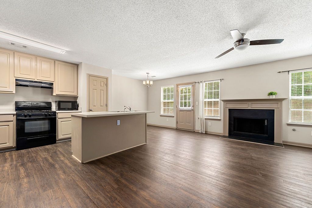 There is a ceiling fan in the living room and a fireplace in the kitchen.