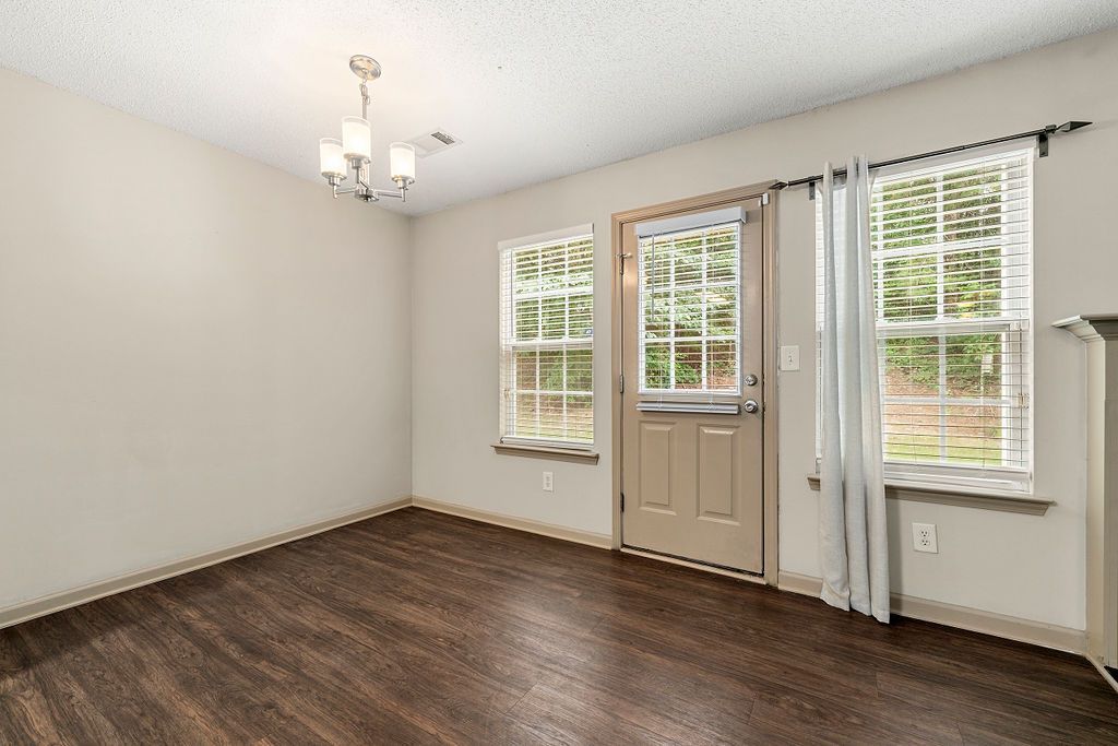 An empty living room with hardwood floors and a chandelier.