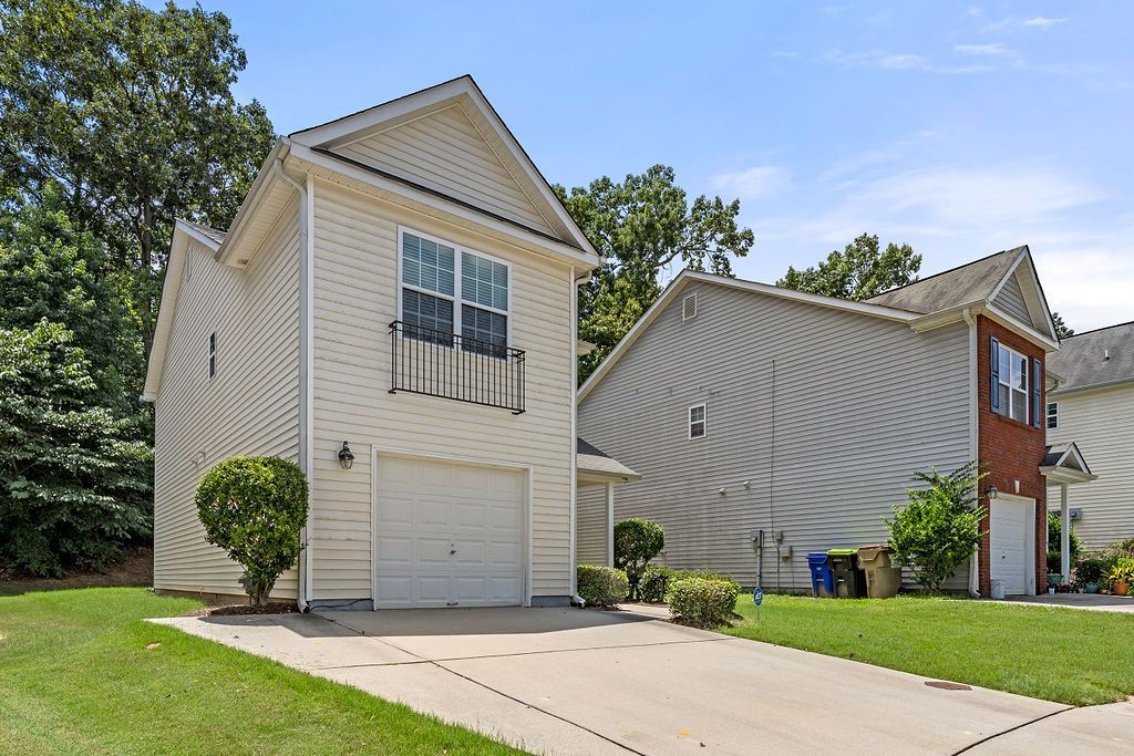 A white house with a garage and a red house in the background
