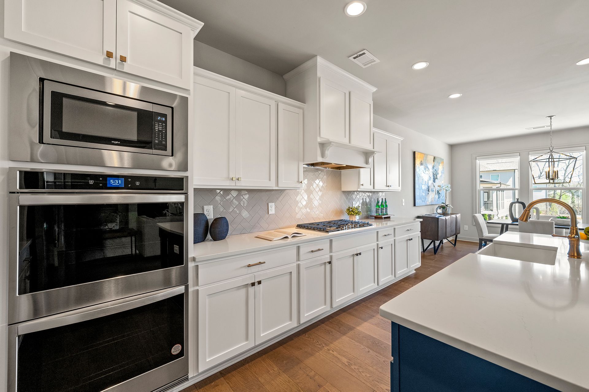 A kitchen with white cabinets , stainless steel appliances , and a large island.