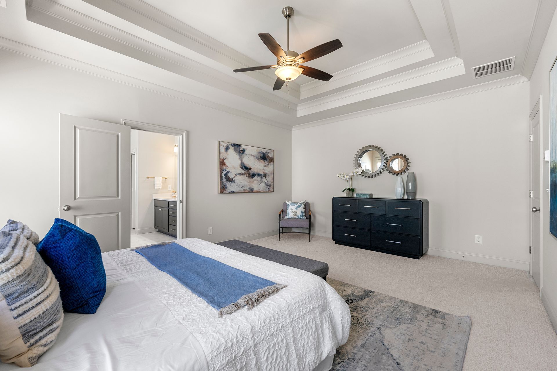 A bedroom with a bed , dresser , chair and ceiling fan.
