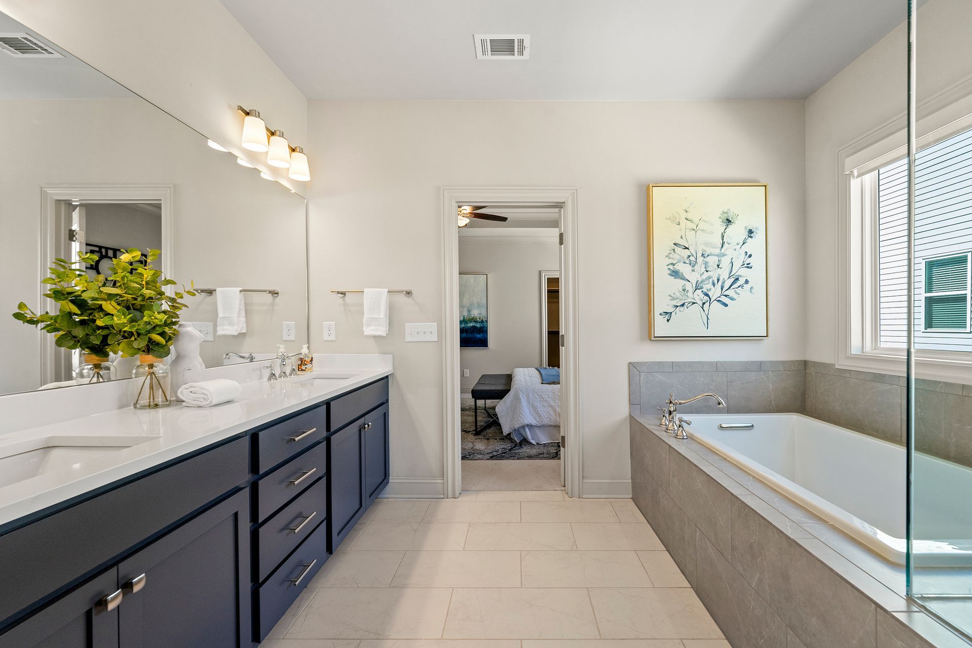 A bathroom with two sinks , a tub , a mirror and a window.