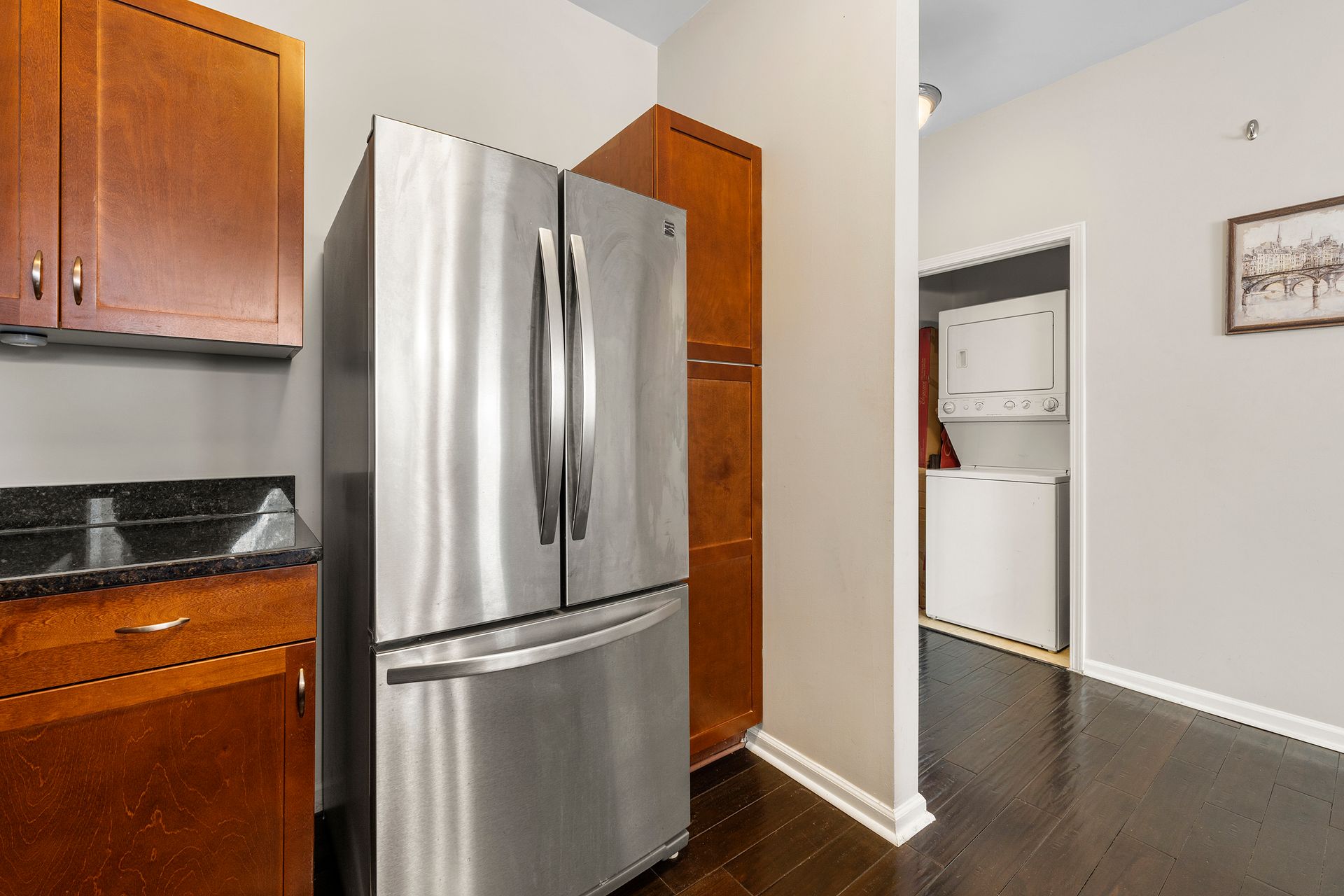 A stainless steel refrigerator is sitting in a kitchen next to a wooden cabinet.
