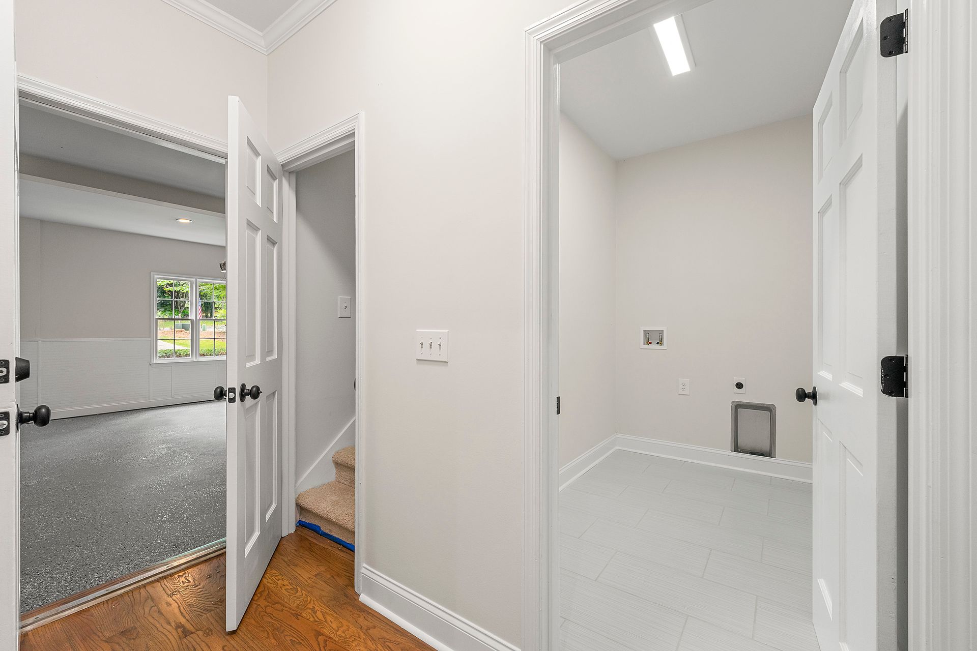 A hallway leading to a laundry room in a house.