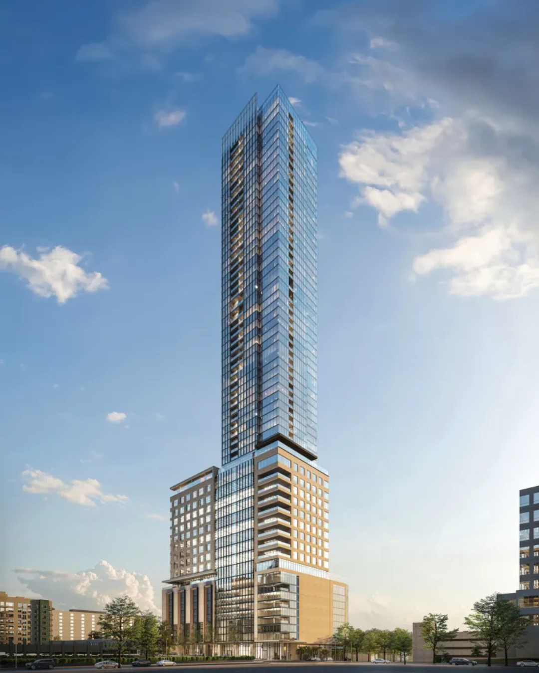 Tall modern skyscraper with glass facade against a blue sky, near other buildings.