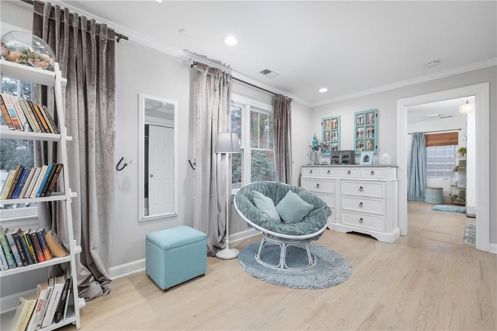 Bedroom with light wooden floors, white furniture, blue accents, and open doorway.
