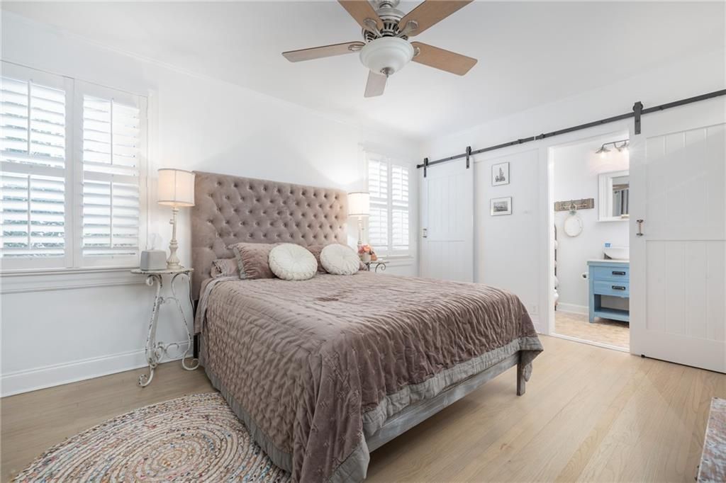 Bedroom with a large bed, light-colored walls, and a view of a bathroom through a sliding door.