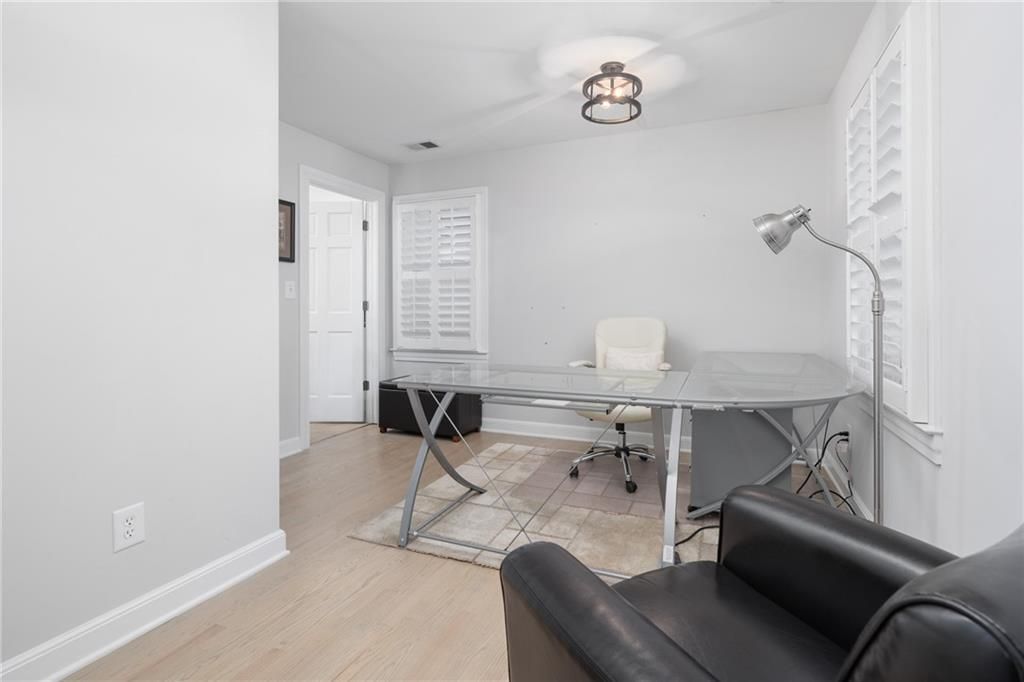 Home office with a glass desk, black chair, and white walls.
