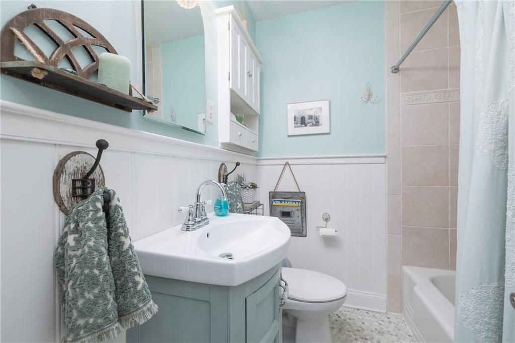 Bathroom with teal and white color scheme; sink, toilet, tub, and wall-mounted cabinet.