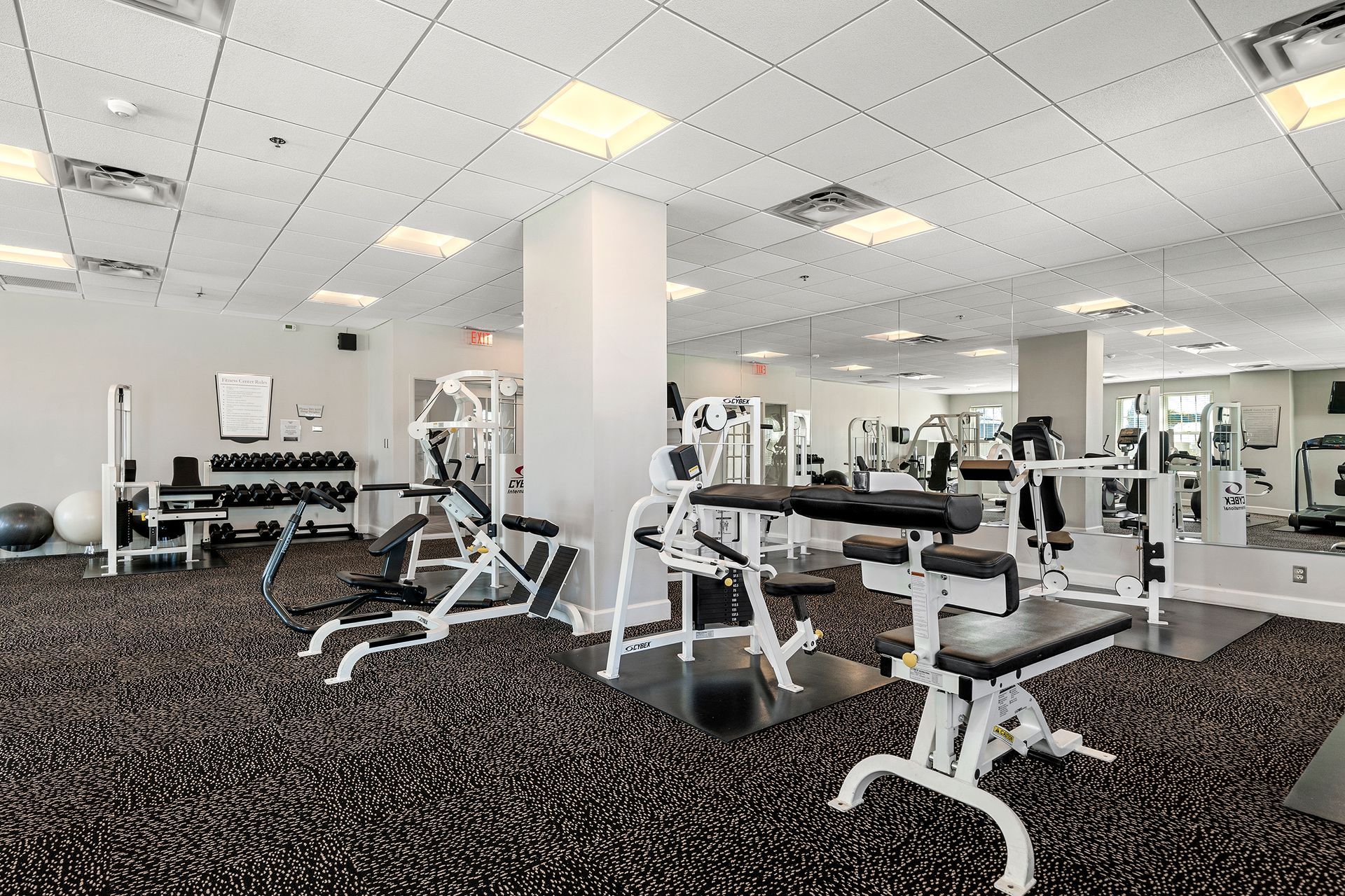 A large gym with a lot of equipment and a lot of mirrors.