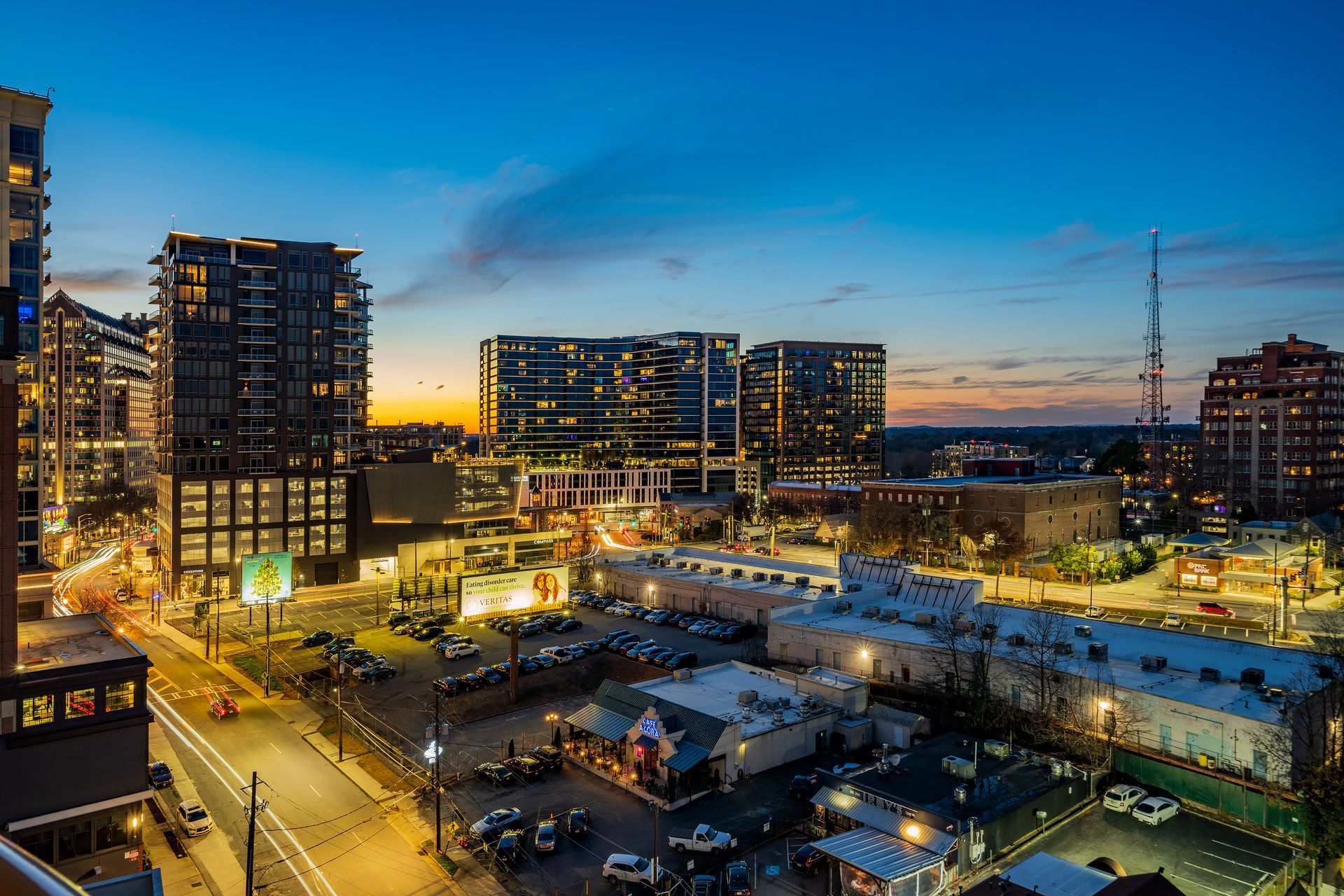 An aerial view of a city at night with lots of buildings and a parking lot.