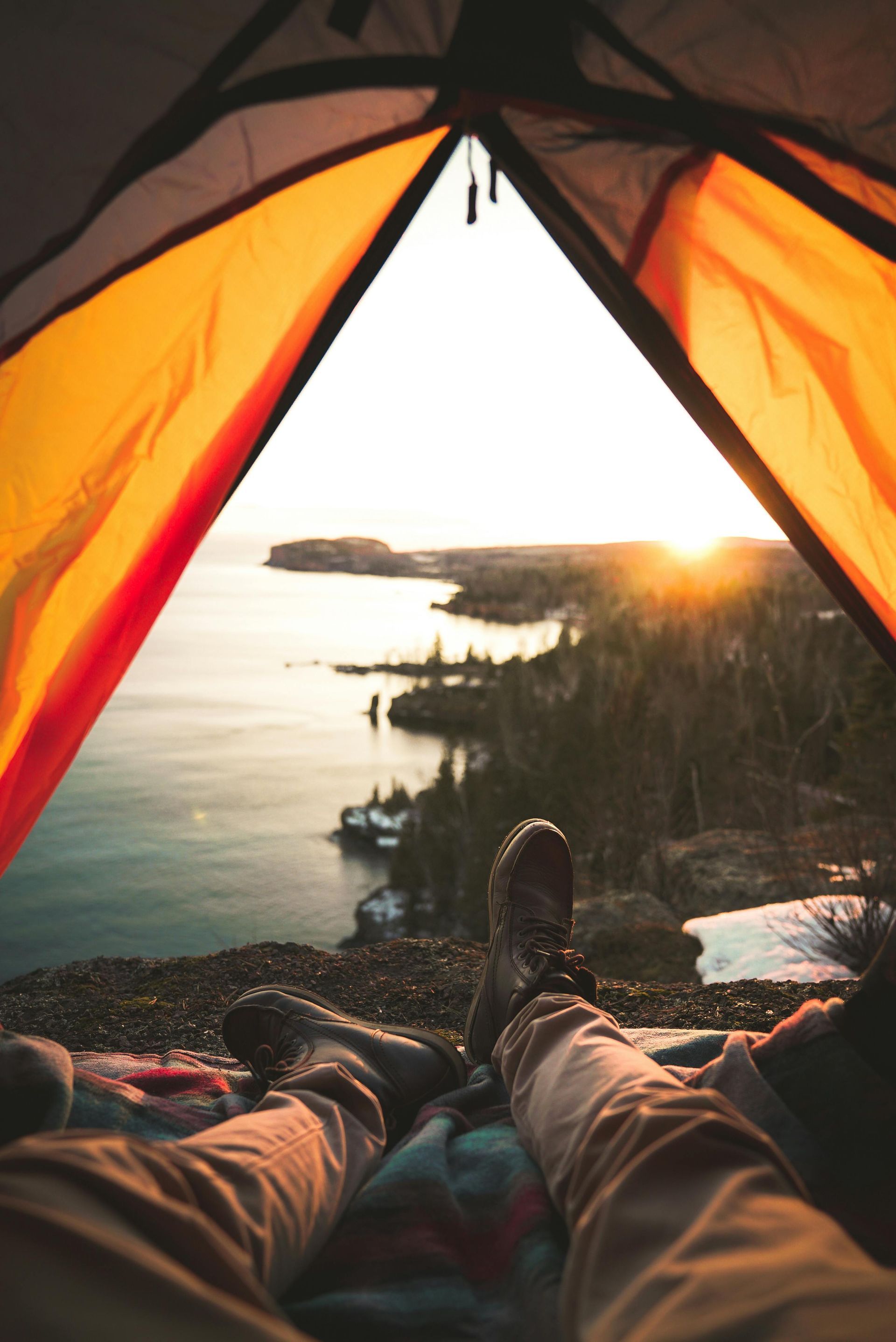 A person is laying in a tent overlooking a body of water