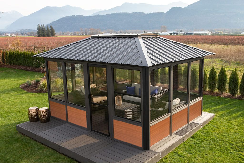 Gazebo with dark frame, brown panels, gray roof, and clear screens on a deck in a yard with a mountain view.