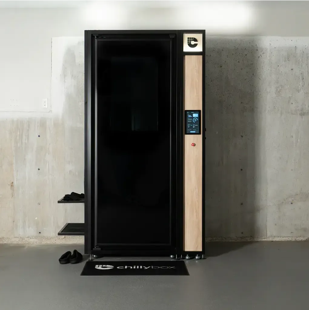 Black vending machine with a digital panel and a door-like front, standing against a concrete wall.