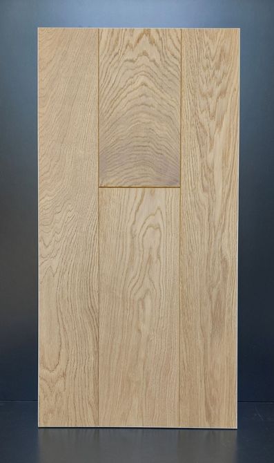 Pannello porta in legno con finitura marrone chiaro. Il pannello è caratterizzato da sezioni rettangolari di diverse dimensioni con venature del legno visibili.
