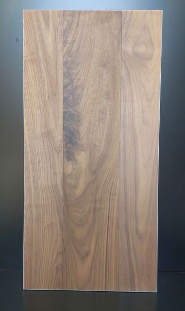 Un pannello di legno rettangolare, con venature verticali nelle tonalità del marrone e del beige.