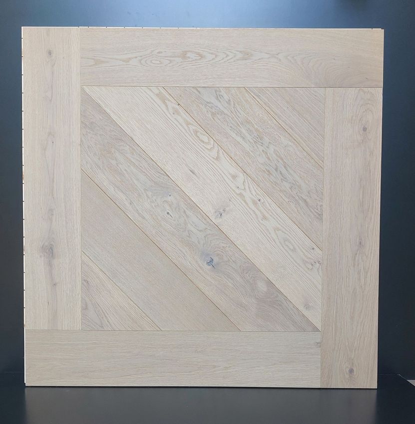 Pavimento in piastrelle di legno chiaro. Il centro presenta un motivo a spina di pesce, incorniciato da un bordo.