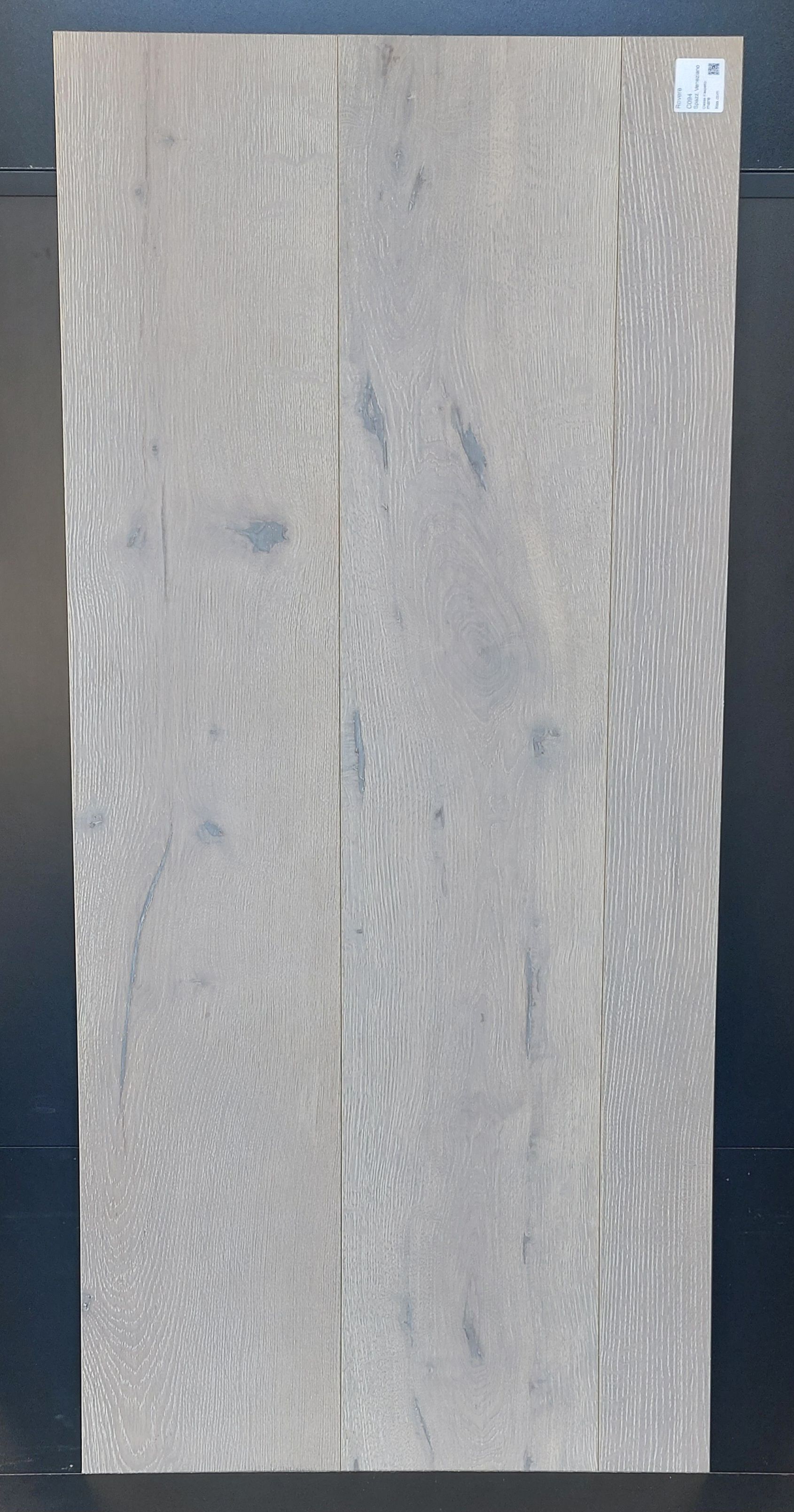 Pavimento in legno grigio chiaro disposto verticalmente. Le venature del legno sono visibili, mostrando la consistenza e le variazioni di colore.