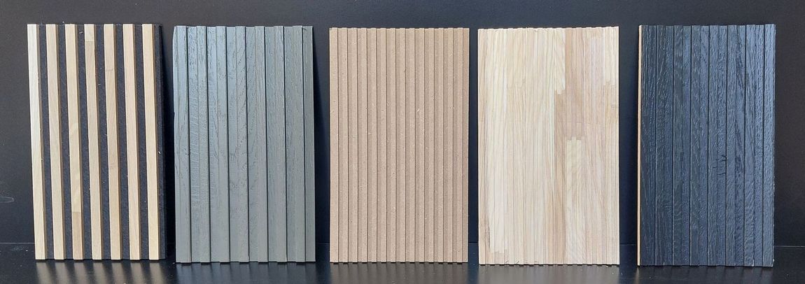 Cinque pannelli rettangolari in legno con superfici testurizzate, disposti uno accanto all'altro. I loro colori variano dal marrone chiaro al grigio scuro.
