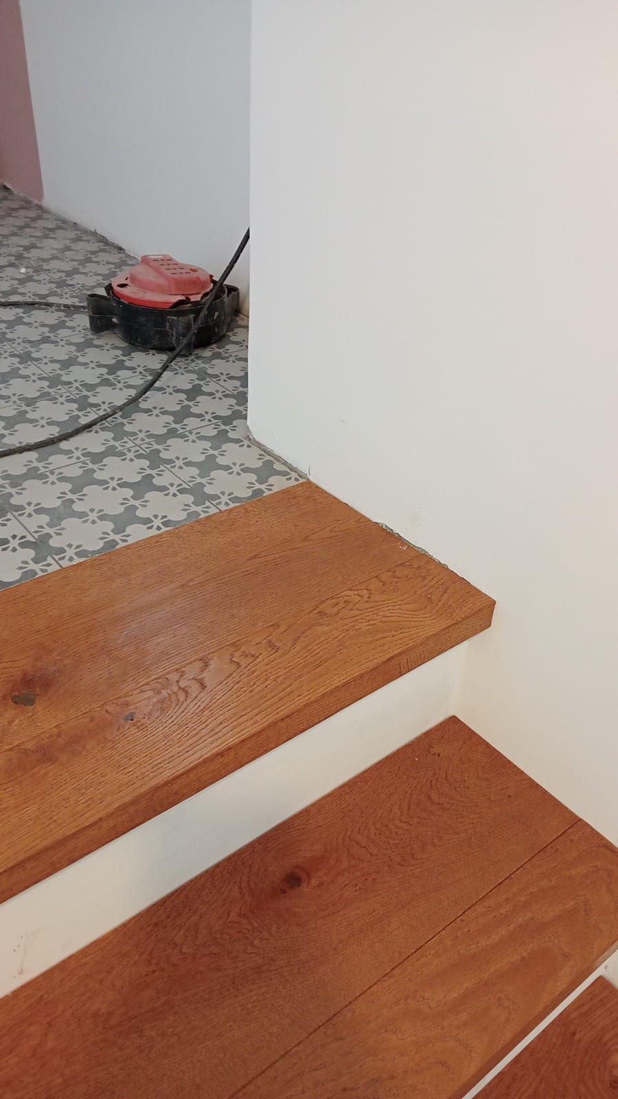 Gradini di scale in legno con una parete bianca sulla destra.