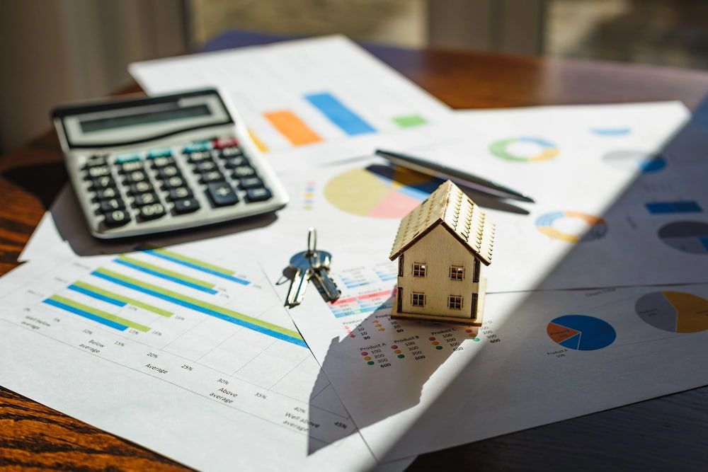 Miniature House With Keys on Financial Charts, Calculator, and Pen — Into Finance Lending Solutions in Coomba Bay, NSW