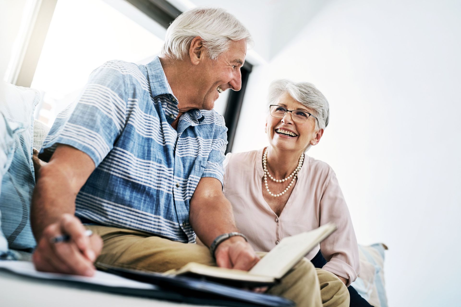 Older Couple Smiling While Looking at a Book and Papers — Into Finance Lending Solutions in Coomba Bay, NSW