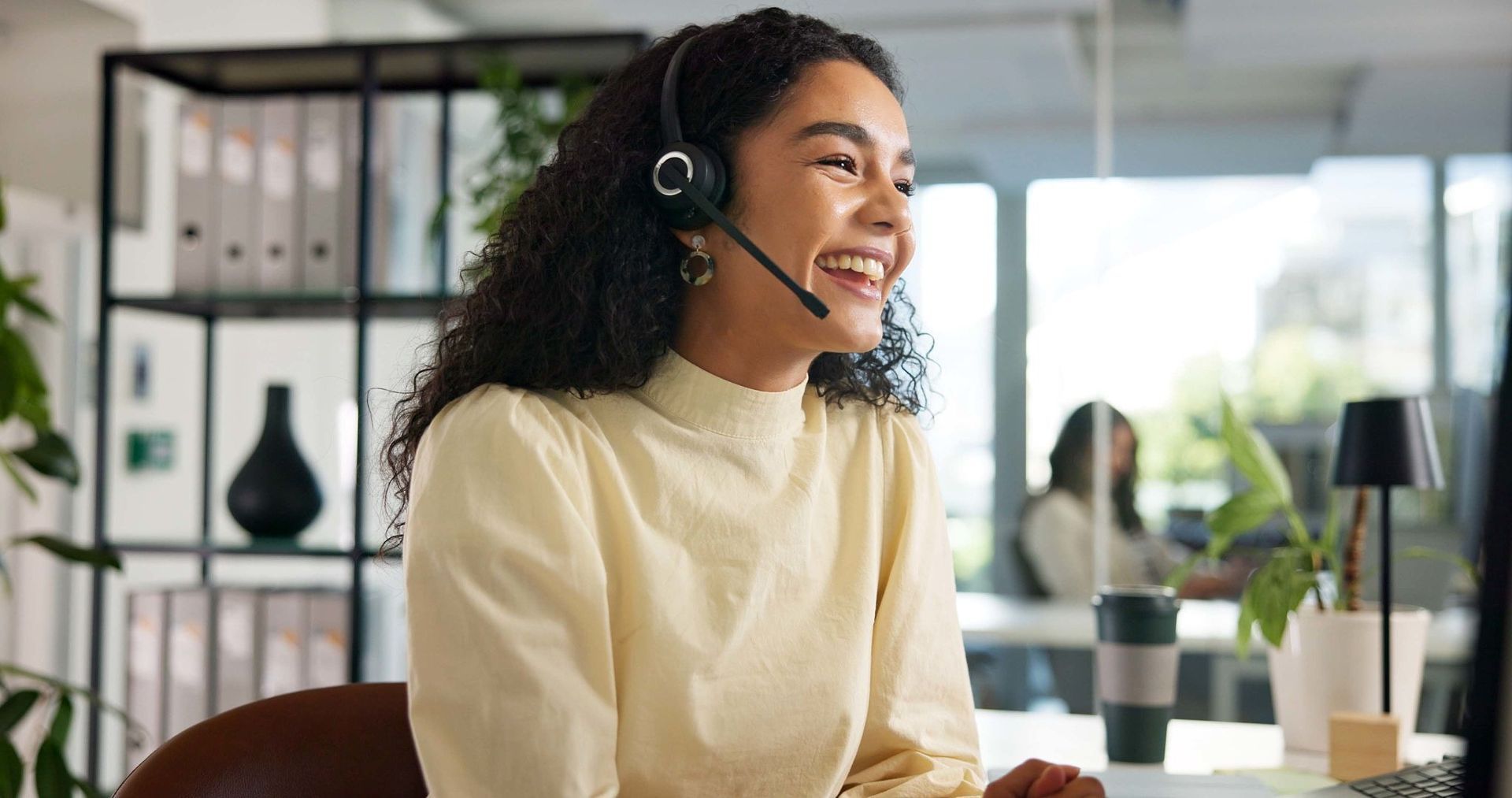 Woman Wearing Headset, Smiling While Working at a Desk in an Office — Into Finance Lending Solutions in Coomba Bay, NSW