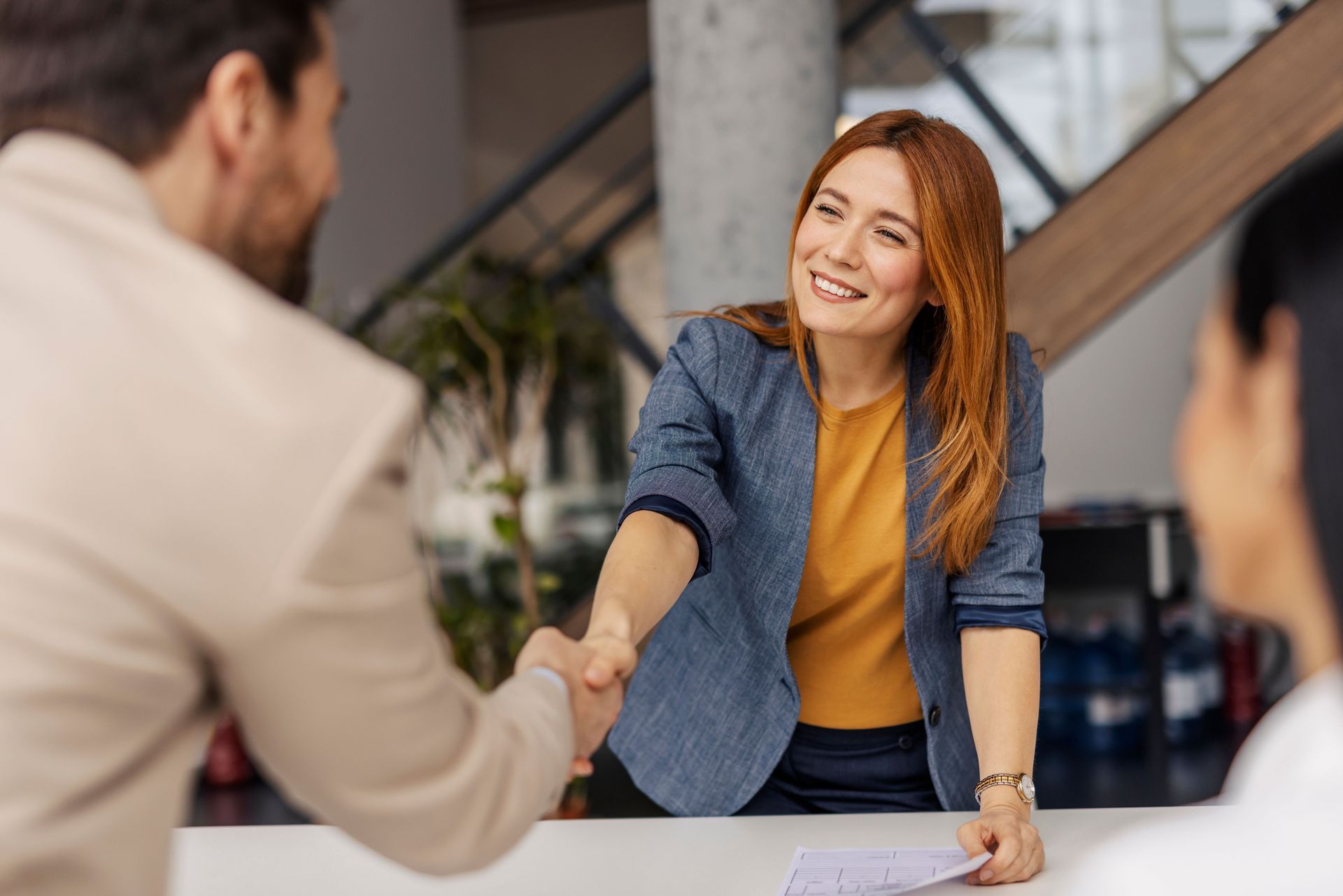 Woman in Blue Blazer Shakes Hands With a Person, Smiling — Into Finance Lending Solutions in Coomba Bay, NSW