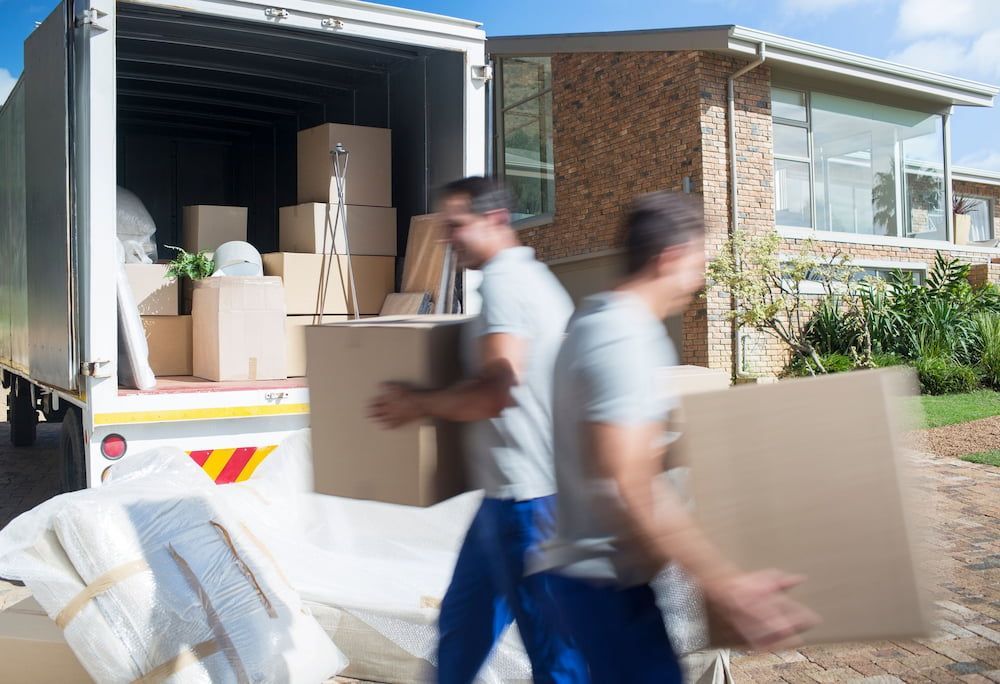 Movers Loading Cardboard Boxes Into a Moving Truck Near a House — Into Finance Lending Solutions in Tuncurry, NSW