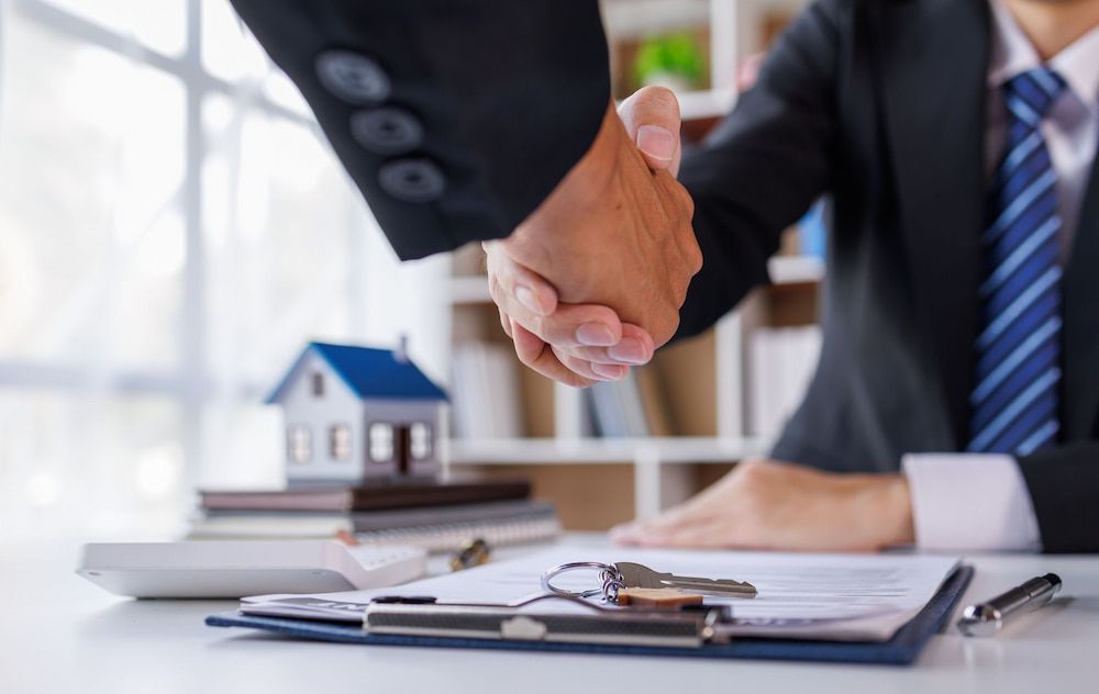 Two People Shaking Hands Over a Real Estate Contract — Into Finance Lending Solutions in Coomba Bay, NSW