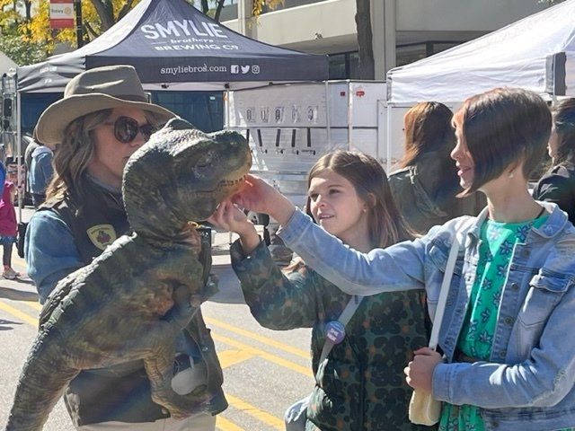Dinosaur meets attendees at a street fair