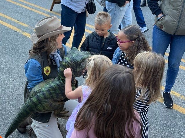 Dinosaur meets children at a street fair