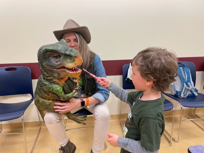 Boy at birthday party brushes dinosaur's teeth