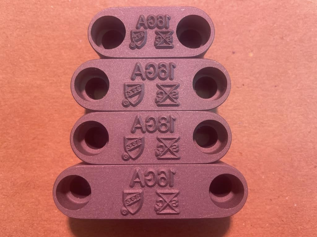 Four stacked, maroon plastic connectors with round holes and stamped symbols.