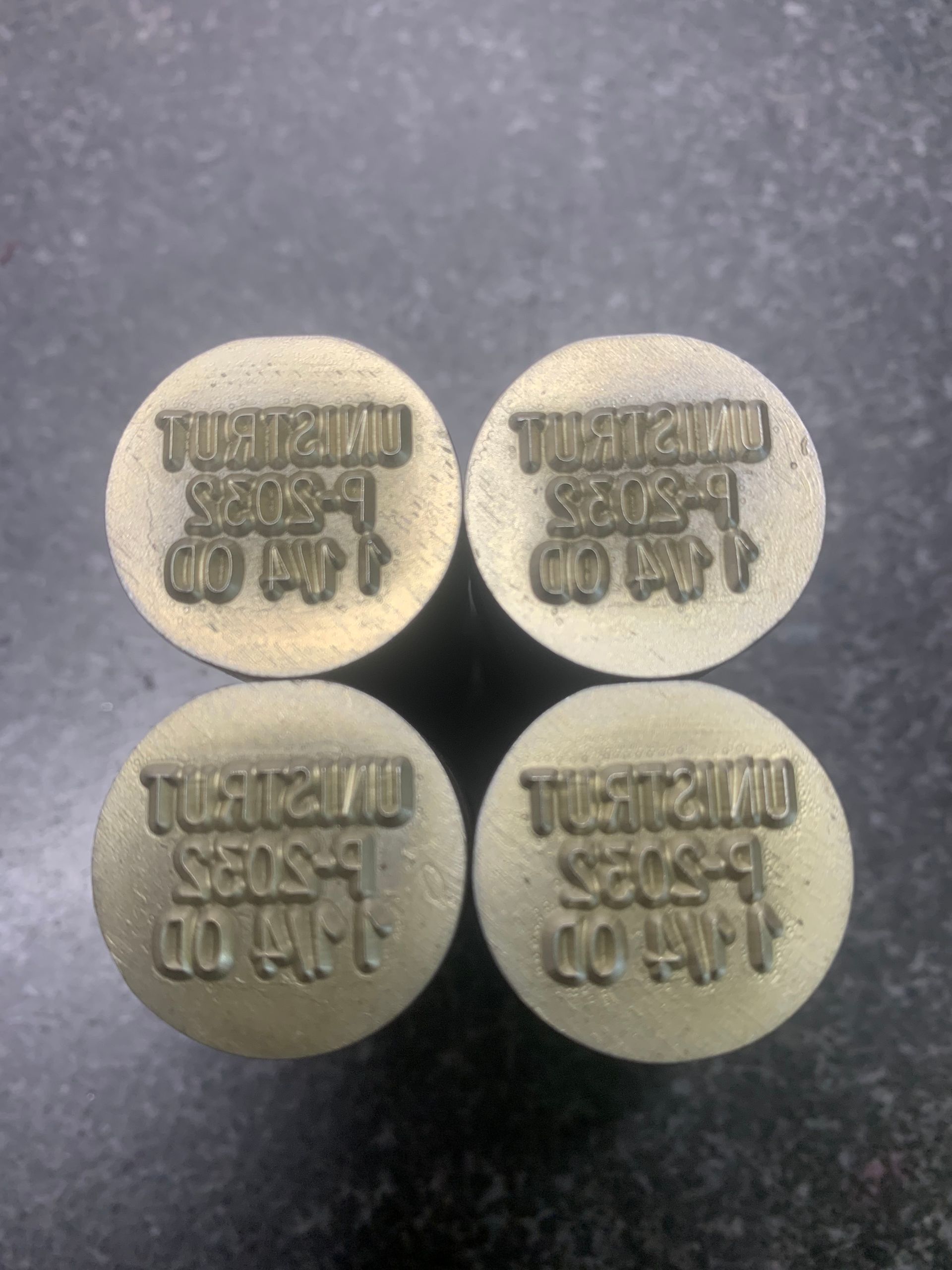Four circular metal stamps, each with raised text reading 