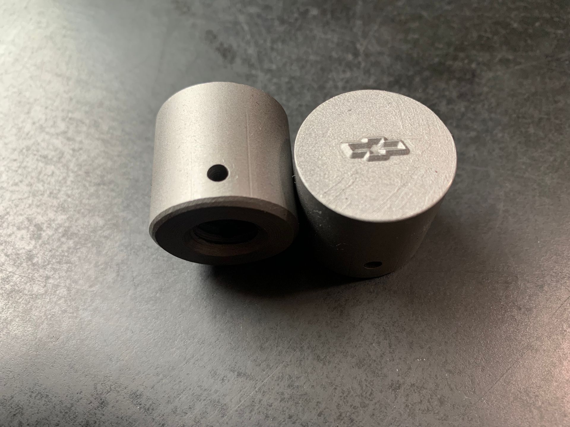 Two cylindrical metal parts, one with Chevrolet logo and hole, the other with a hole.