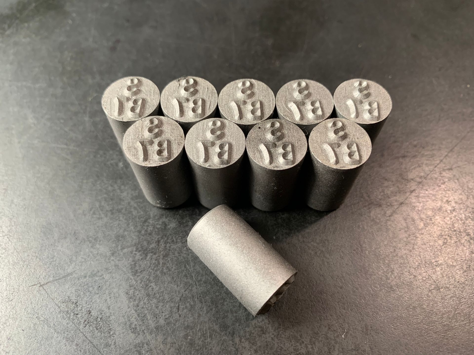 Ten metal stamps with the number 8 and Thai script arranged in a triangle, one stamp separate.