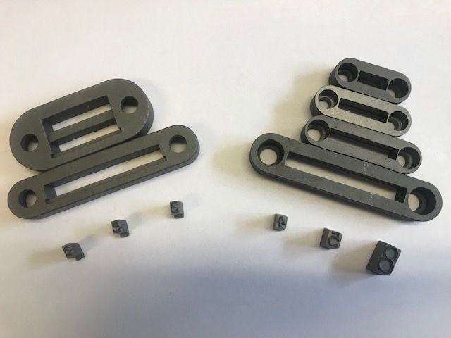 Four dark brown, rectangular plastic connectors stacked, each with holes and symbols.