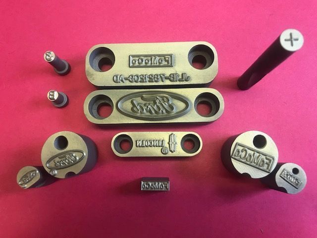 Various metal stamping tools arranged on a pink surface.